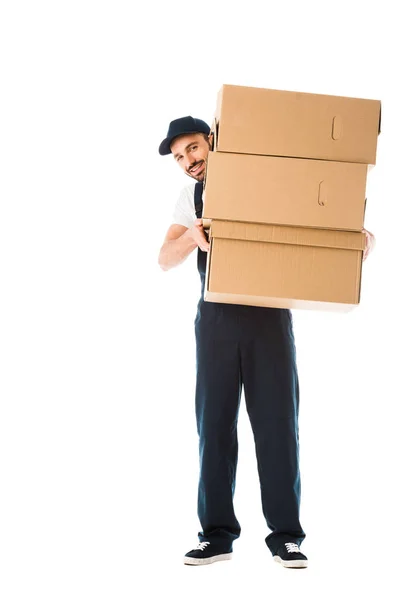 Усміхнений чоловік доставки тримає картонні коробки і дивиться на камеру ізольовано на білому — стокове фото