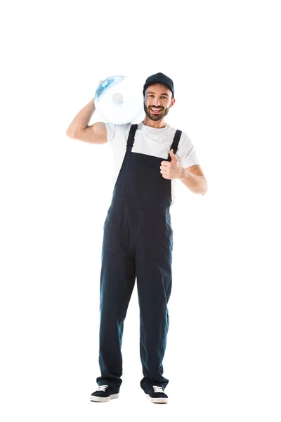 Alegre repartidor hombre sosteniendo botella de agua y mostrando el pulgar hacia arriba aislado en blanco - foto de stock