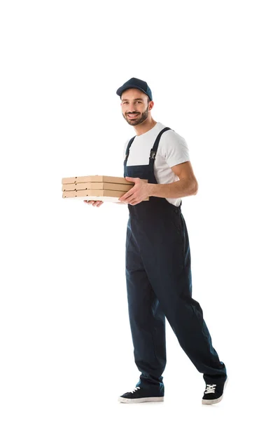 Cheerful delivery man carrying pizza boxes and smiling at camera isolated on white — Stock Photo