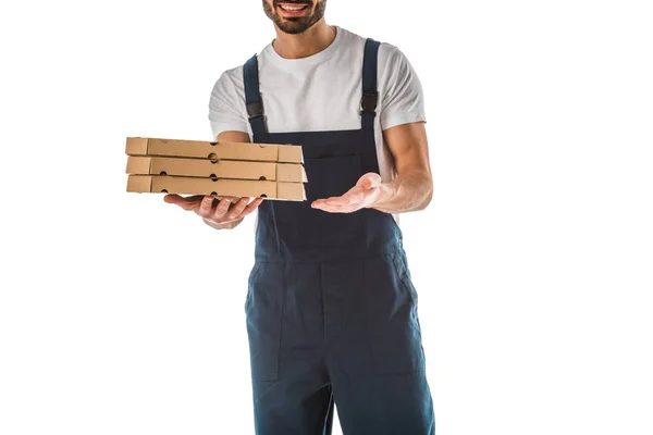 Vista parcial del repartidor sonriente sosteniendo cajas de pizza aisladas en blanco - foto de stock