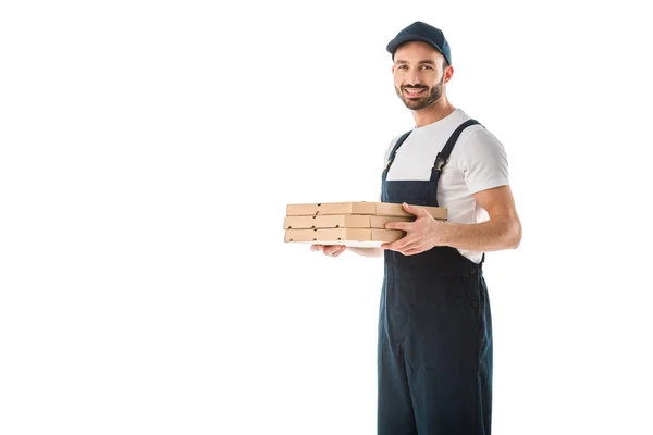 Guapo repartidor sosteniendo cajas de pizza y sonriendo a la cámara aislado en blanco - foto de stock