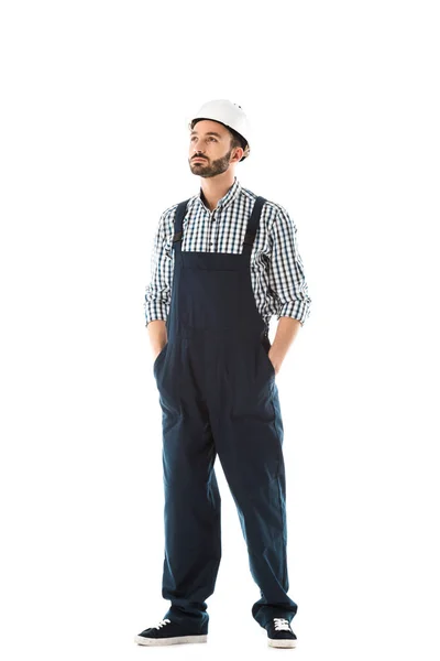 Serious construction worker with hands in pockets looking up isolated on white — Stock Photo