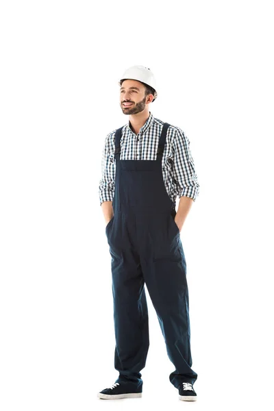 Beau travailleur de la construction souriant avec les mains dans les poches regardant isolé sur blanc — Photo de stock