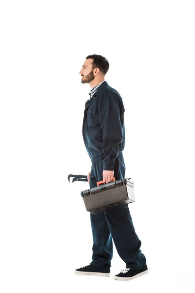 Side view of plumber holding adjustable wrench and toolbox isolated on white — Stock Photo