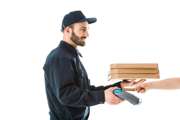 Vista parcial de la mano femenina con tarjeta de crédito cerca de entrega alegre hombre celebración terminal de pago y cajas de pizza aislados en blanco — Stock Photo