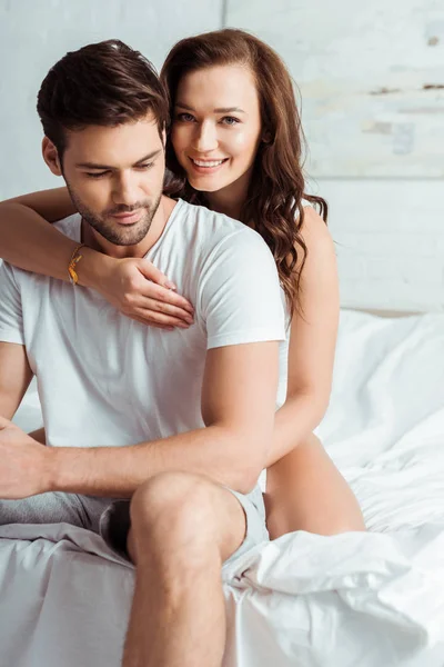 Happy brunette girl looking at camera while hugging handsome man at home — Stock Photo