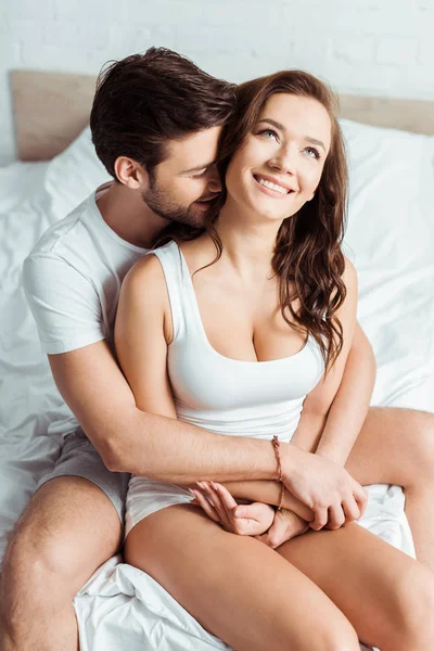 Красивий чоловік обіймає щасливу дівчину в спальні — стокове фото