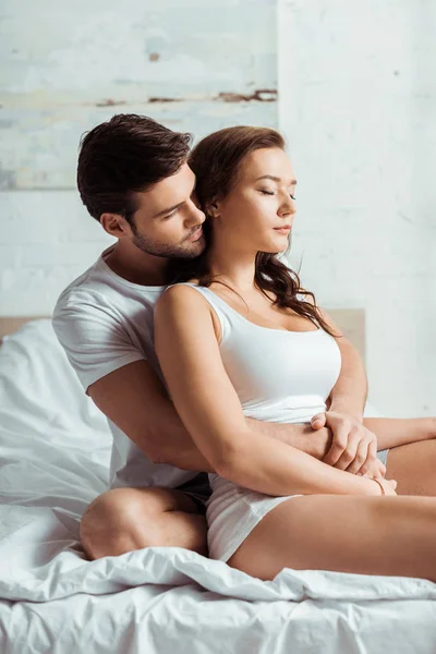 Schöner Mann umarmt attraktive Freundin mit geschlossenen Augen — Stockfoto