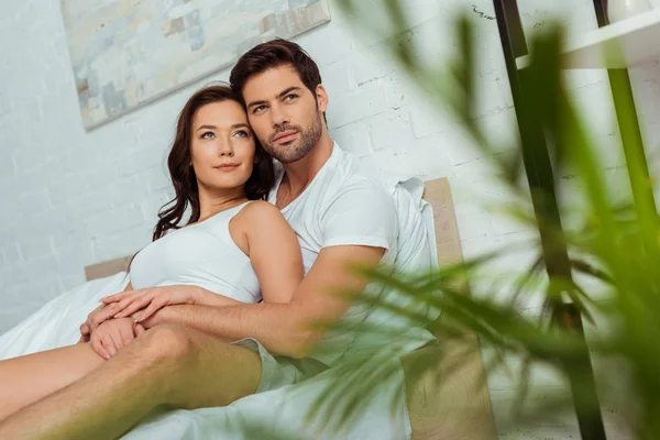Selective focus of handsome man lying in bed with attractive woman — Stock Photo