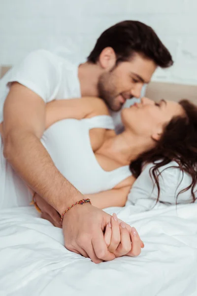 Selective focus of couple holding hands while lying on bed — Stock Photo