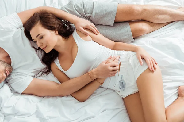 Top view of attractive girl lying on bed with man and holding hands — Stock Photo