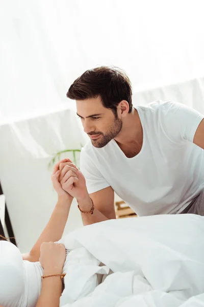 Cropped view of woman holding hands with handsome boyfriend at home — Stock Photo