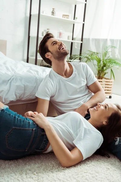 Donna felice guardando bello uomo sorridente mentre seduto su tappeto — Foto stock