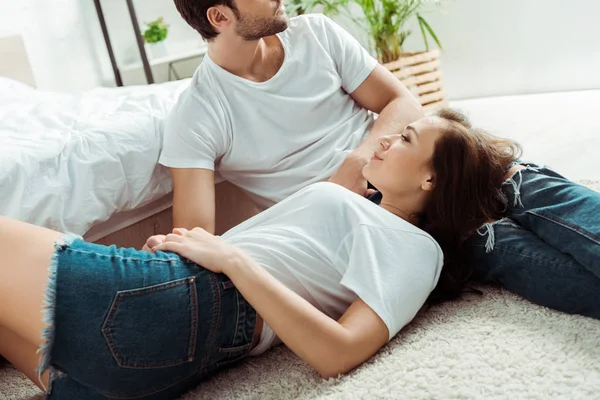 Femme gaie couchée sur le tapis près du petit ami dans la chambre — Photo de stock