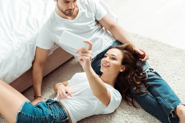 Vista aerea di donna allegra prendendo selfie con l'uomo in camera da letto — Foto stock