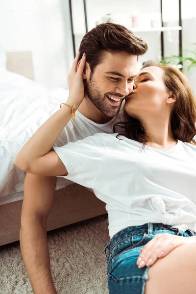 Namorada beijando bochecha de namorado feliz no quarto — Fotografia de Stock