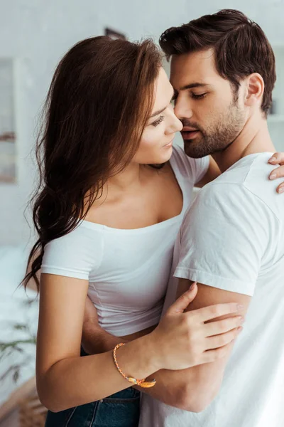 Hombre guapo abrazo y mirando atractiva novia en blanco camiseta - foto de stock