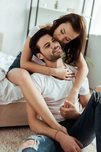 Счастливая молодая женщина с закрытыми глазами сидит на кровати и обнимает мужчину — стоковое фото