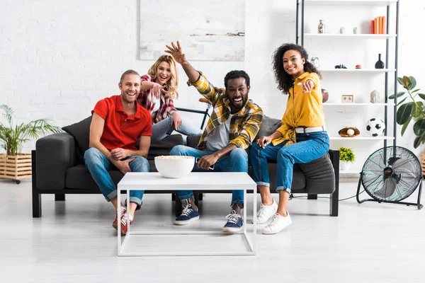 Fröhlich lachende multikulturelle junge Leute, die auf der Couch sitzen und Zeit miteinander verbringen — Stockfoto