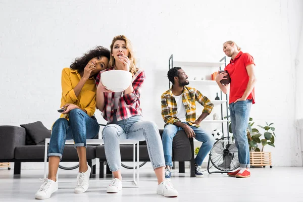 Dois homens multiculturais falantes e duas mulheres comendo pipocas enquanto assistem jogo — Fotografia de Stock