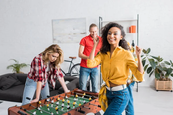 Jovens e felizes amigos multiétnicos tendo tempo alegre juntos enquanto joga futebol de mesa — Fotografia de Stock