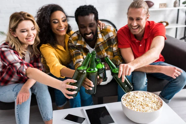 Selektiver Fokus glücklicher multikultureller Freunde beim Anstoßen im Wohnzimmer — Stockfoto