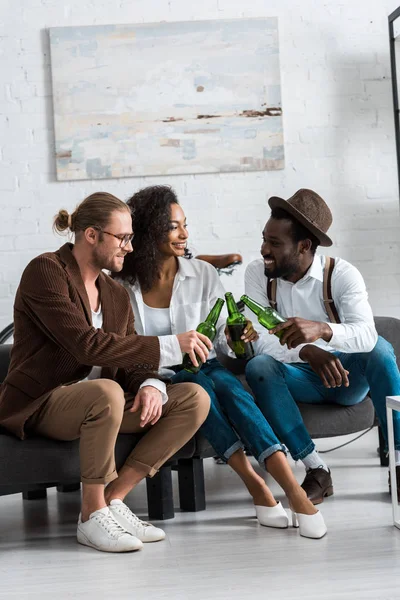 Fröhliche multikulturelle Männer, die mit fröhlichen afrikanisch-amerikanischen Mädchen im Wohnzimmer anstoßen — Stockfoto