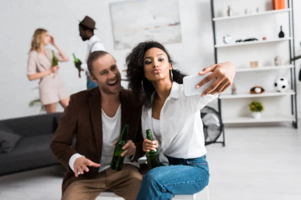 Selective focus of african american girl with duck face taking selfie with cheerful man — Stock Photo