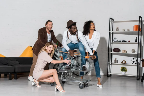 Bel homme afro-américain en chapeau équitation dans le panier près d'amis heureux — Photo de stock