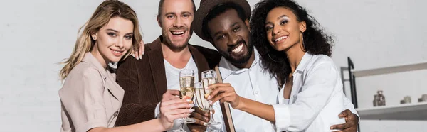 Tiro panorâmico de amigos multiculturais felizes segurando copos de champanhe — Fotografia de Stock