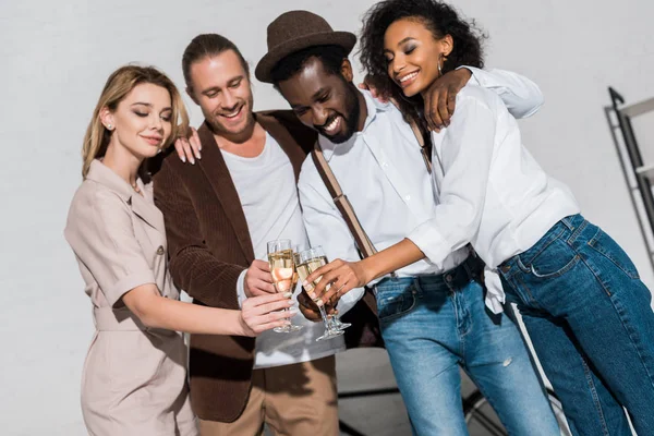 Vue à angle bas d'amis multiculturels heureux souriant tout en cliquetis verres à champagne — Photo de stock