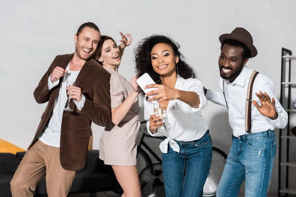 Felice ragazza afro-americana prendendo selfie con gli amici in possesso di bicchieri di champagne — Foto stock