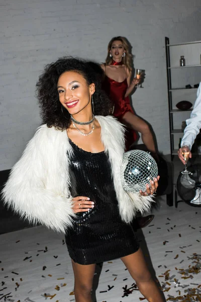 Selective focus of happy african american girl holding disco ball while standing near friends — Stock Photo