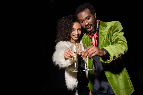 Selective focus of cheerful african american girl and handsome african american man holding champagne glasses isolated on black — Stock Photo