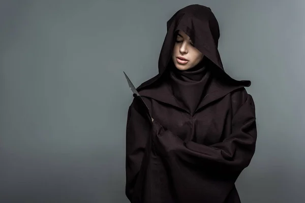 Frau im Todeskostüm hält Messer isoliert auf Grau — Stockfoto