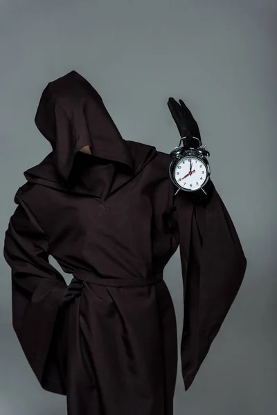 Woman in death costume holding alarm clock isolated on grey — Stock Photo