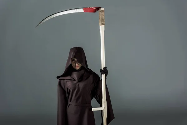 Woman in death costume holding scythe on grey — Stock Photo