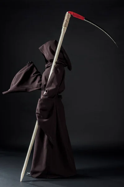 Seitenansicht einer Frau im Todeskostüm mit Sense auf Schwarz — Stockfoto