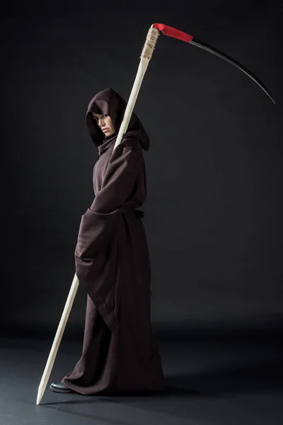 Full length view of woman in death costume holding scythe on black — Stock Photo