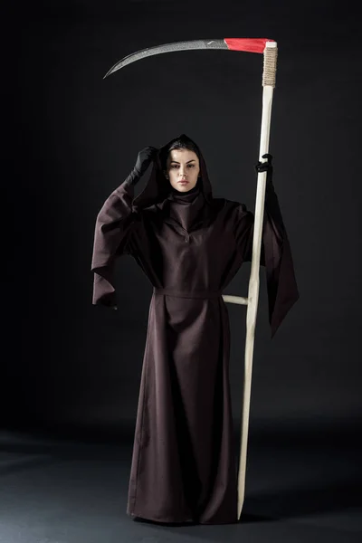 Вид в полный рост женщины в костюме смерти, держащей косу на черном — стоковое фото