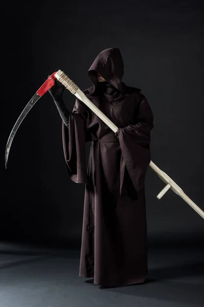 Full length view of woman in death costume holding scythe on black — Stock Photo