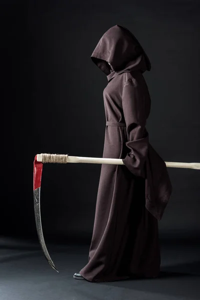 Full length view of woman in death costume holding scythe on black — Stock Photo