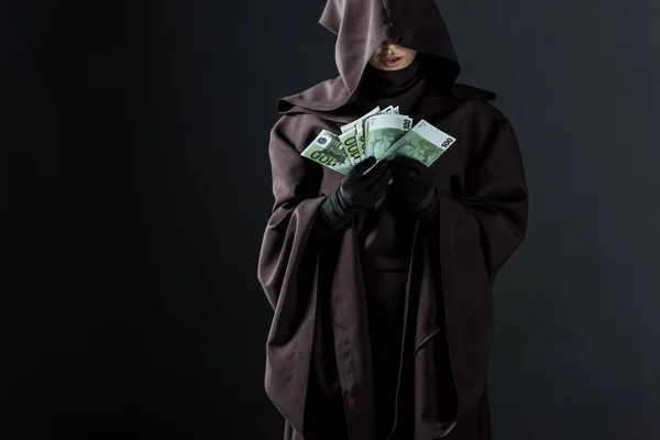 Vue recadrée de la femme en costume de mort tenant les billets en euros isolés sur noir — Photo de stock