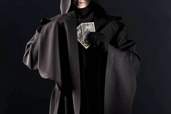 KYIV, UCRANIA - 18 DE ABRIL DE 2019: vista recortada de la mujer en traje de la muerte sosteniendo cartas del tarot aislados en negro - foto de stock