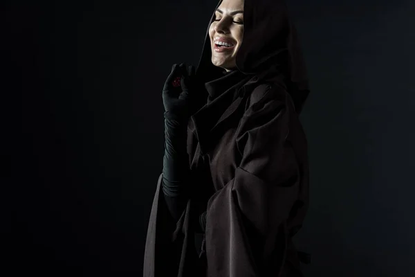 Laughing woman in death costume holding dice isolated on black — Stock Photo