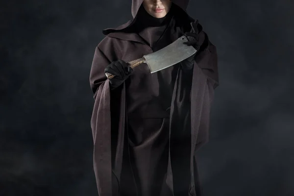 Partial view of woman in death costume holding cleaver on black — Stock Photo