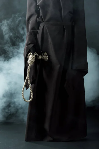 Cropped view of woman in death costume holding hanging noose on black — Stock Photo