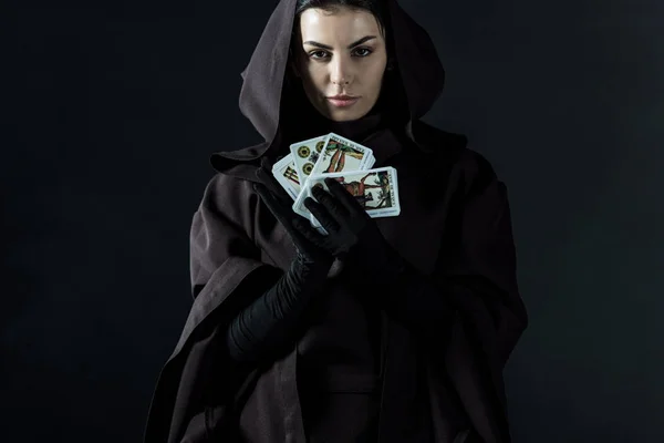 KYIV, UCRÂNIA - 18 de abril de 2019: visão frontal de uma mulher em traje de morte segurando cartas de tarô isoladas em preto — Fotografia de Stock