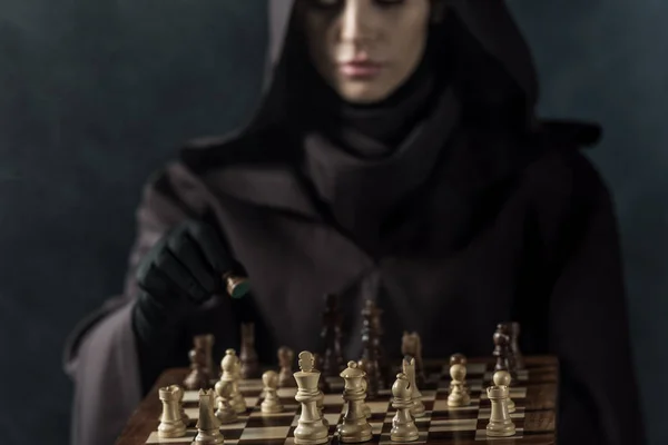 Cropped view of woman in death costume playing chess on black — Stock Photo