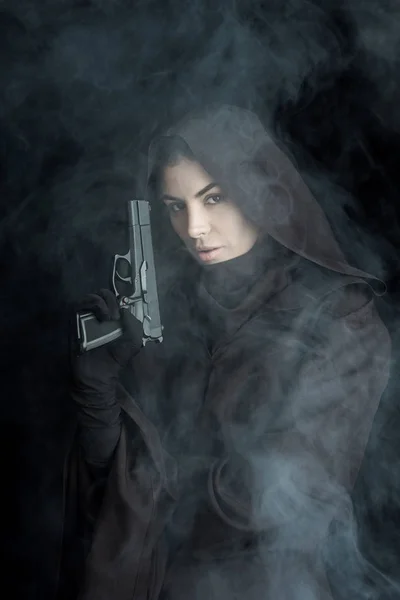 Woman in death costume holding gun and looking at camera on black — Stock Photo